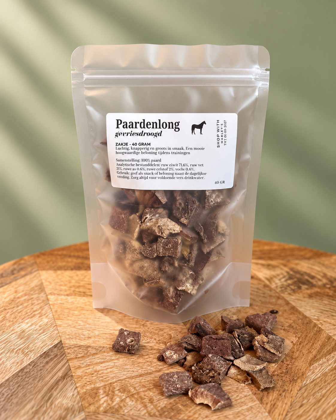 Marley’s gevriesdroogde paardenlong 40 gram, zakje met losse stukjes paardenlong op een houten plateau tegen zachtgroene achtergrond