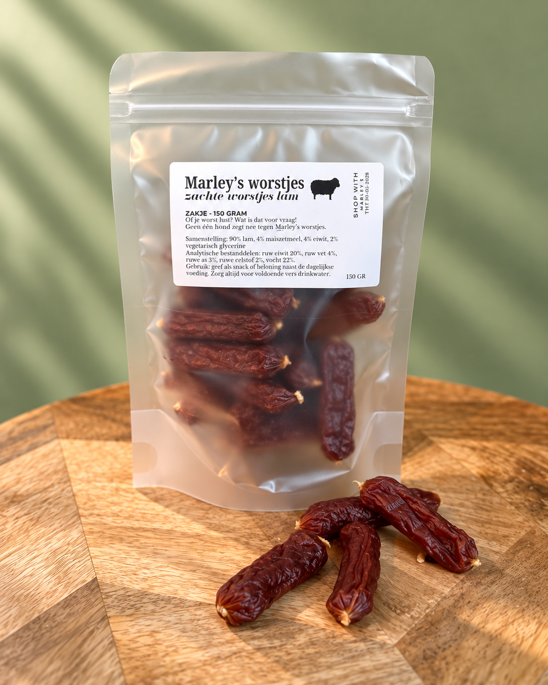 Marley’s zachte worstjes lam 150 gram in hersluitbaar zakje, met zachte lamsworstjes op een houten plateau voor een groene achtergrond